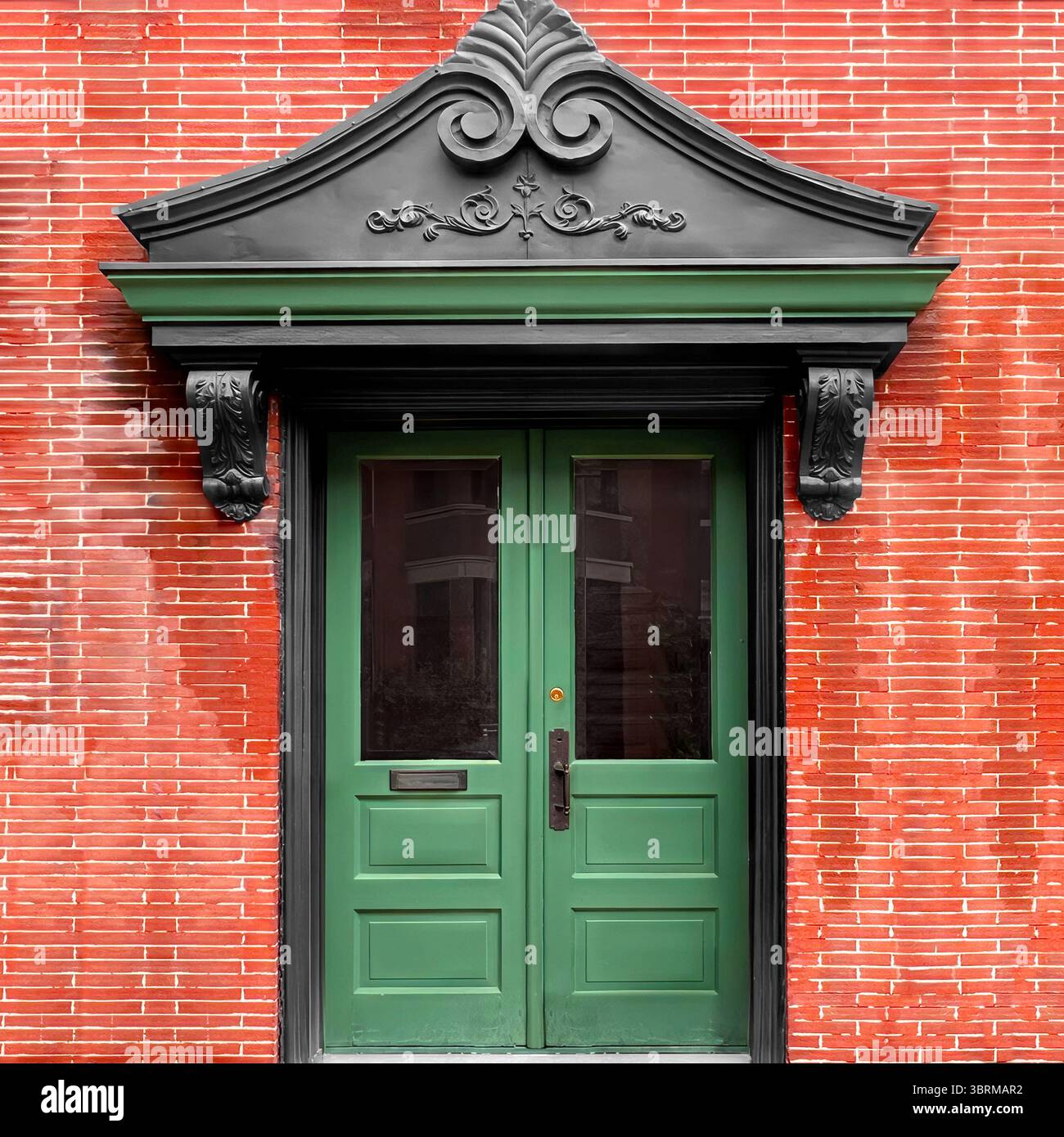 Grüne Doppeltüren mit kunstvollem schwarzen Giebel vor rotem Backstein – ein markanter architektonischer Eingangsbereich im historischen Chicago. - Smartphone-aufgenommenes Stockfoto