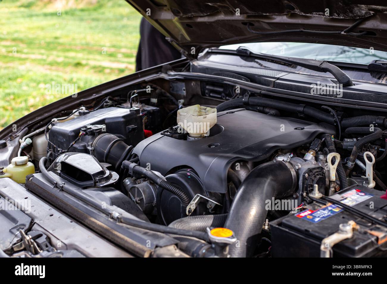 Pkw-Motor mit offener Motorhaube, Motorkomponenten und Trichter zum Einfüllen von Motoröl. Stockfoto