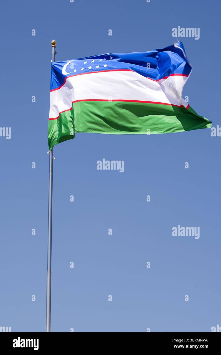 Nationalflagge von Usbekistan flattert in der Brise mit blauem Himmel Hintergrund Stockfoto
