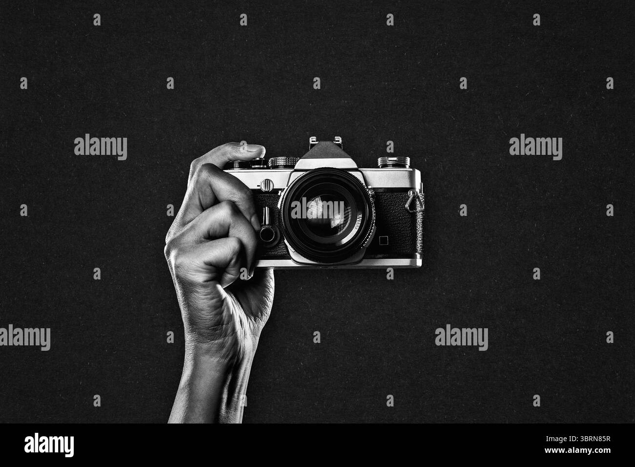 Hand hält Vintage-Kamera in Schwarzweiß auf strukturiertem Papierhintergrund, Kopierraum Stockfoto Hand hält Vintage-Kamera in Schwarzweiß auf strukturiertem Papierhintergrund, Kopierraum Stockfoto