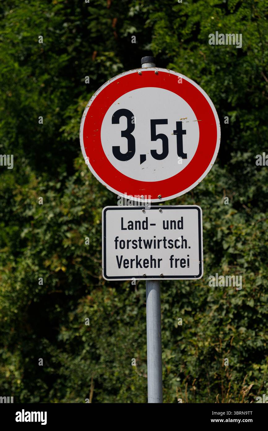 Ein Metallmast trägt ein 3,5 t Gewichtsbegrenzungsschild und eine deutsche Land- und forstwirtschaft. Verkehr frei' Zeichen vor einem Hintergrund von dichtem grünem Laub Stockfoto