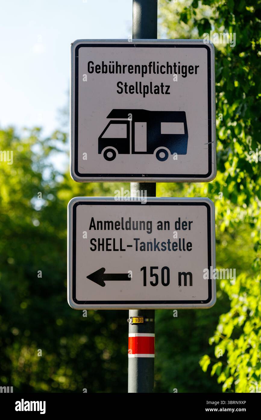 Zwei deutsche Straßenschilder an einer Stange. Das obere Schild weist auf einen kostenpflichtigen Parkplatz hin, das untere führt zu einer Shell-Station, die 150 m entfernt ist. Stockfoto