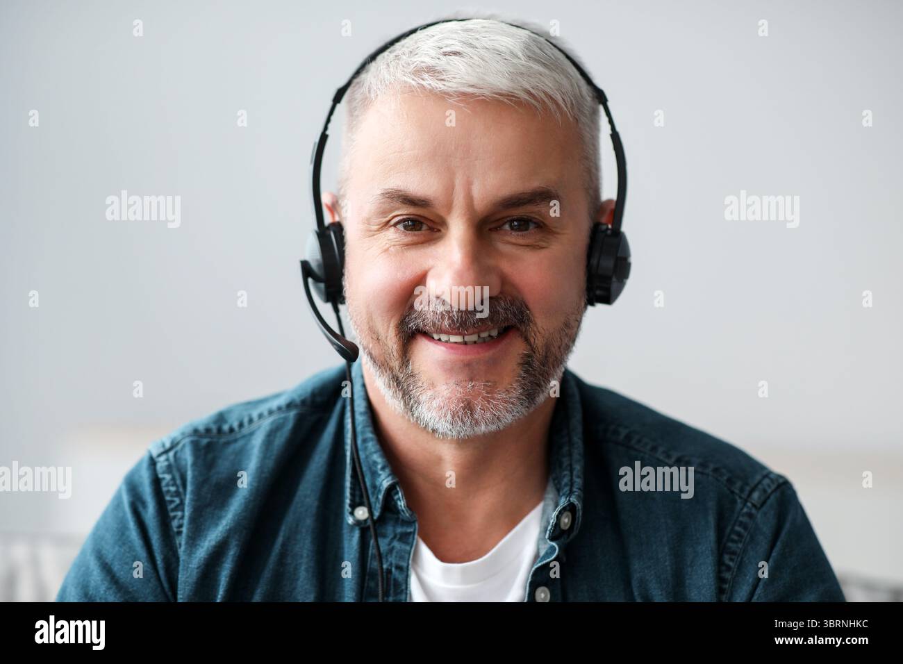 Lächelnder älterer Mann, der eine Videokonferenz mit einem Headset führt Stockfoto