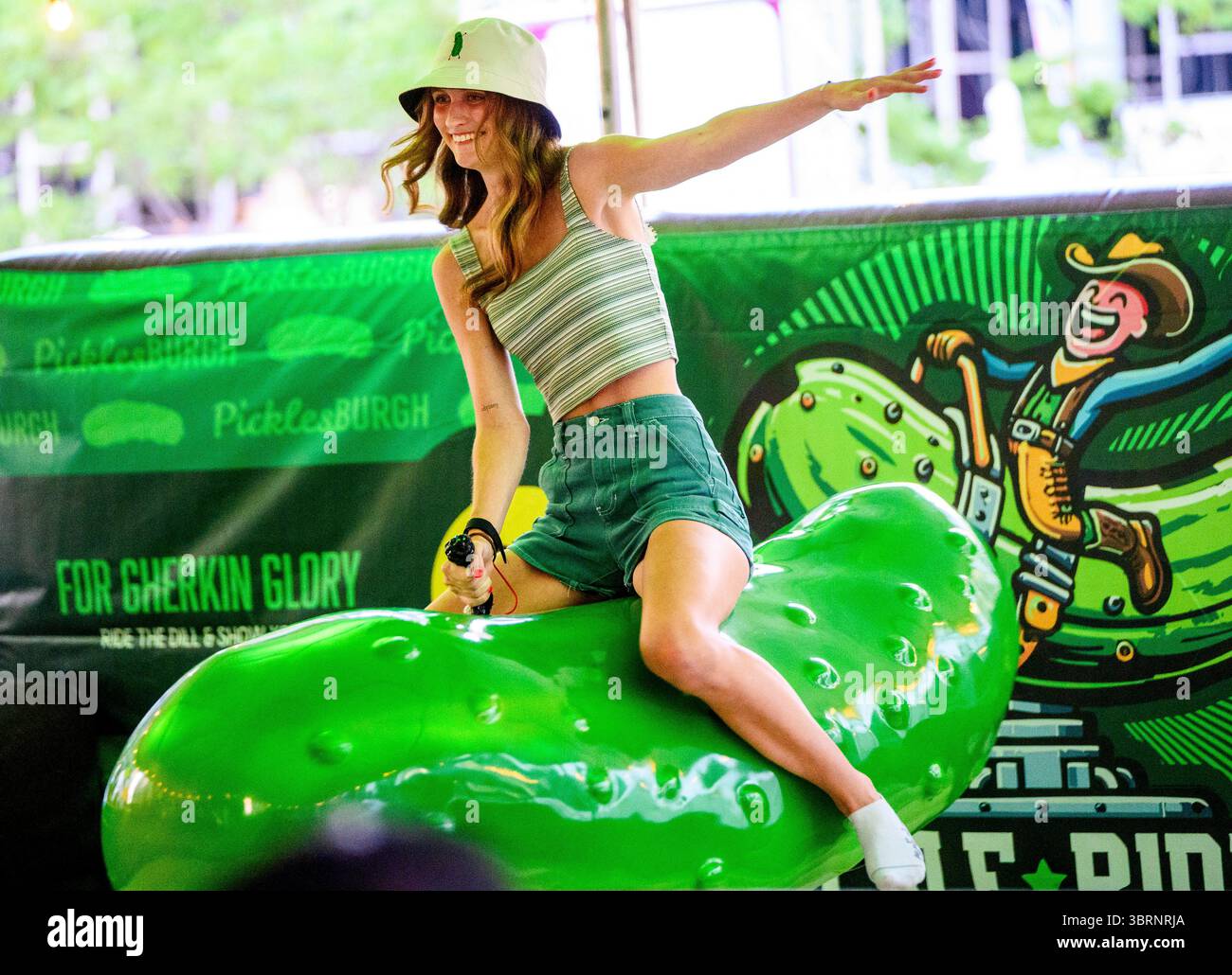 Pittsburgh, Usa. Juli 2025. Besucher des Picklesburgh-Events versuchen ihr Glück beim Fahren einer Mechanik im Rahmen des zehnten Jubiläums von Picklesburgh am Sonntag, den 13. Juli 2025 in der Innenstadt von Pittsburgh. Foto: Archie Carpenter/UPI Credit: UPI/Alamy Live News Stockfoto