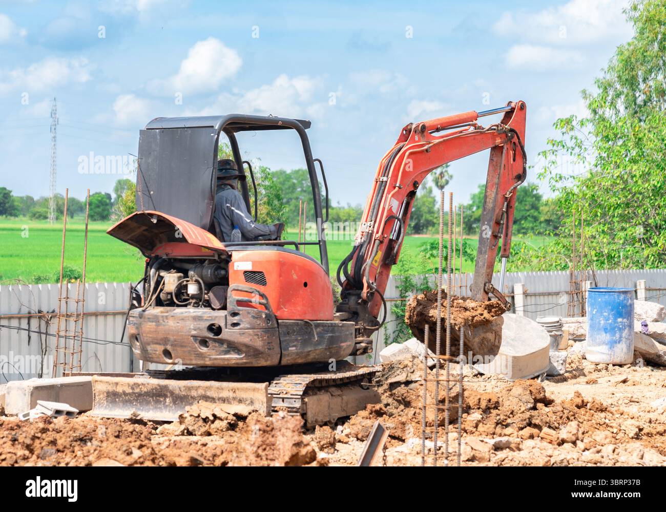 Ein Kompaktbagger entfernt den Boden vom Fundament des Pfahls. Stockfoto