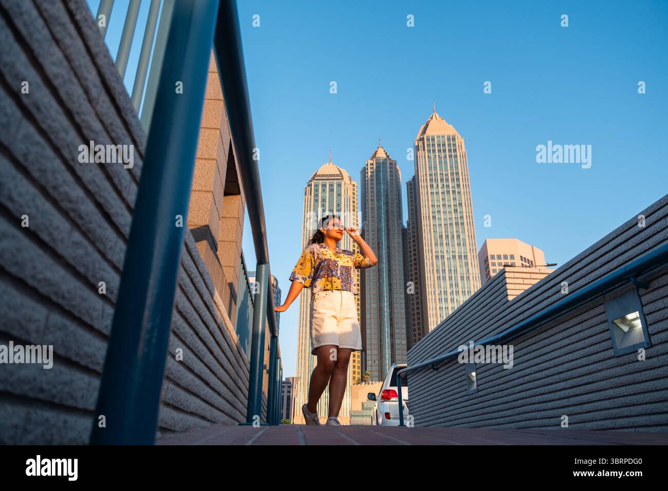Junge Reisende, die Abu Dhabi Corniche mit Highrise Building Hintergrund erkunden Stockfoto