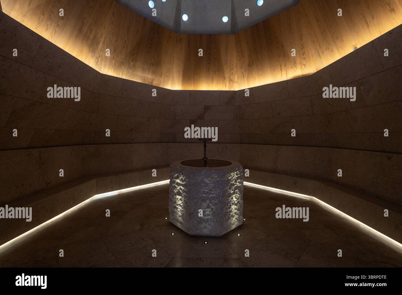 Moderne Kapelle mit achteckiger Taufschrift, dunklem und stimmungsvollem Innendesign-Hintergrund Stockfoto