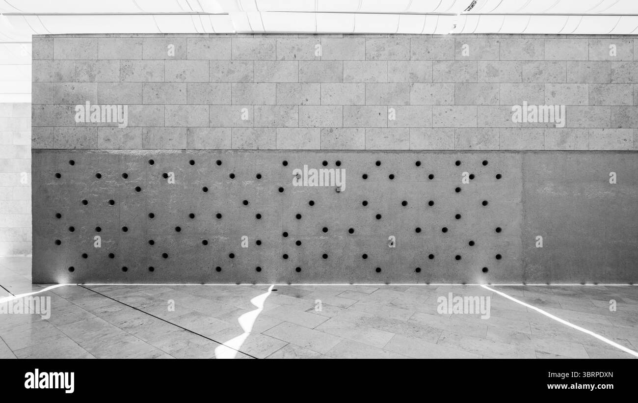 Betonwand im Industriestil mit Löchern, ungleichmäßige Perforationen in der Wand, moderne Architekturfassade mit Belüftung - horizontale Betonwand hinten Stockfoto