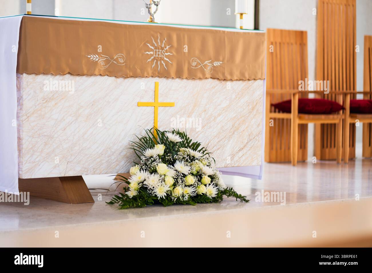 Heiliger Kirchenaltar mit gelbem Kreuz und weißen Blumen Stockfoto