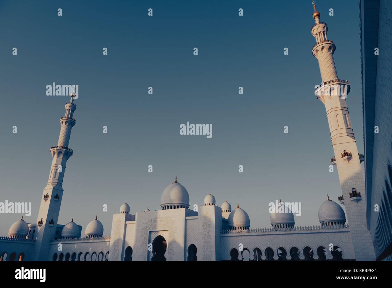 Filmischer Blick auf die große Moschee in der Dämmerung mit weißem Marmor und verzierten Minaretten, Kopierraum für Text oder Grafiken, Eid-Poster-Hintergrund Stockfoto