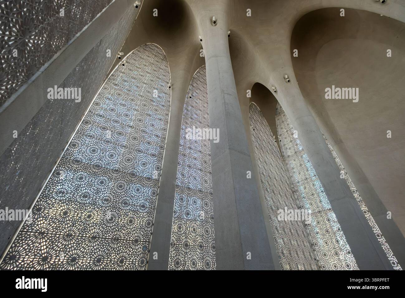 Komplexe architektonische Säulen mit kunstvollen Gitterfenstern unter einer Bogendecke, die eine Kombination aus geometrischen Mustern und natürlichem Licht zeigen Stockfoto