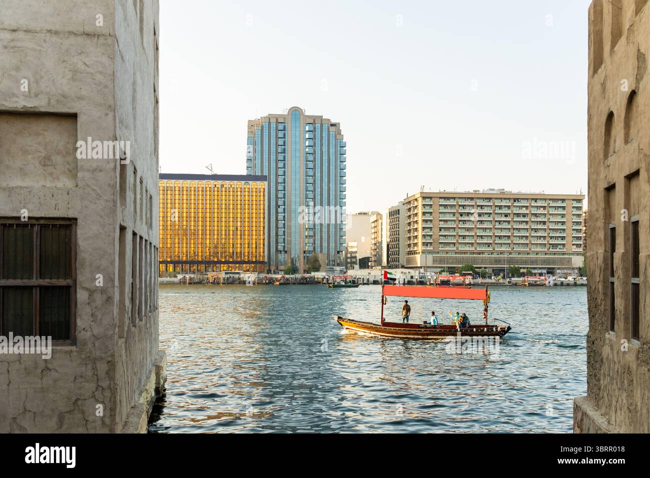 Blick auf die Abra Boote im Dubai Creek mit dem alten Dubai und der Skyline von Deira bei Sonnenuntergang, Blick auf die Golden Hour Skyline Stockfoto