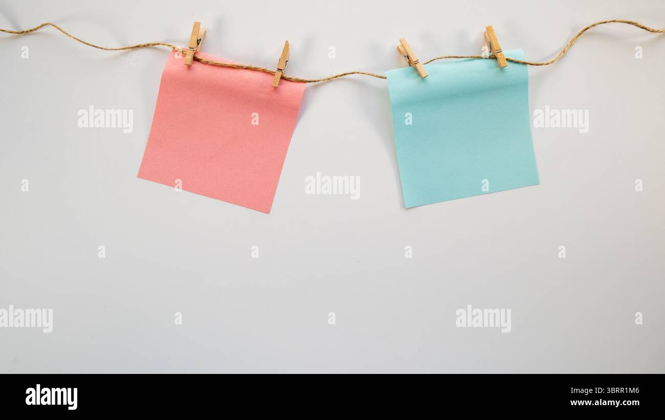Cure Pastellblau und rosa Post-it Notizen hängen an der Schnur, auf weißem Hintergrund, Junge oder Mädchen - Baby Geschlecht zeigen kreativen Posterhintergrund, leeres pac Stockfoto