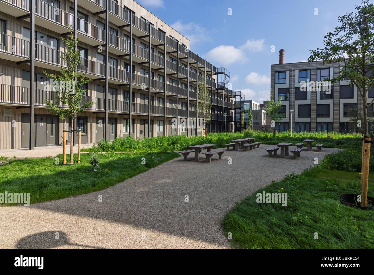 Ein gemeinschaftlicher Innenhof mit Picknicktischen in temporären modularen Häusern in Utrecht, Niederlande, veranschaulicht eine moderne Lösung für städtisches Wohnhaus Stockfoto