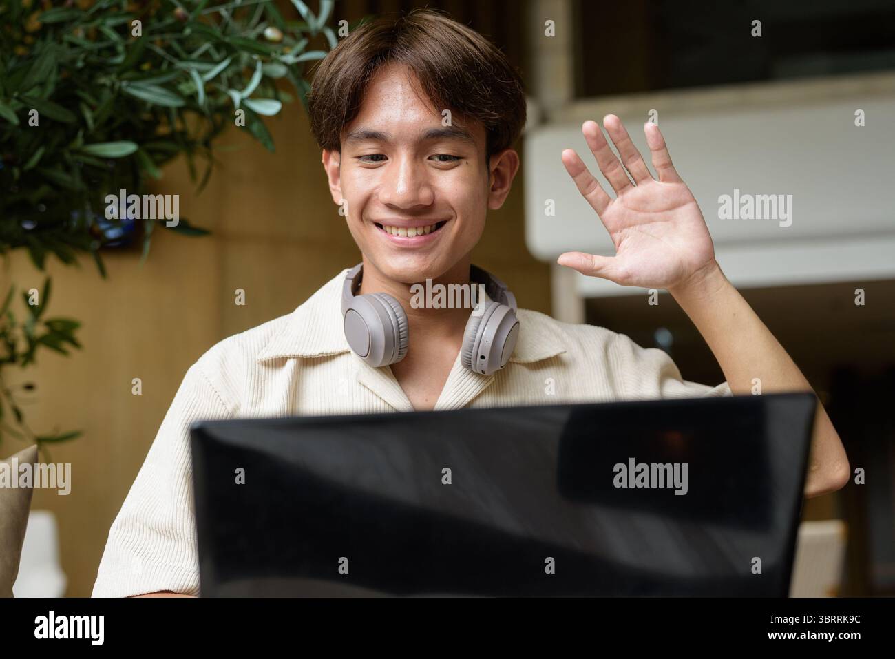 Niedlicher asiatischer Studentenmann, der in einem modernen Café sitzt Stockfoto