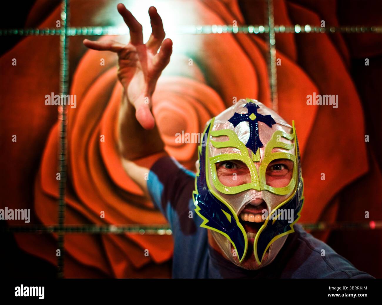 Ein Mann posiert vor einem Wandgemälde, während er eine lucha libre mexikanische Wrestling Maske in Cancun, Mexiko, trägt. Stockfoto