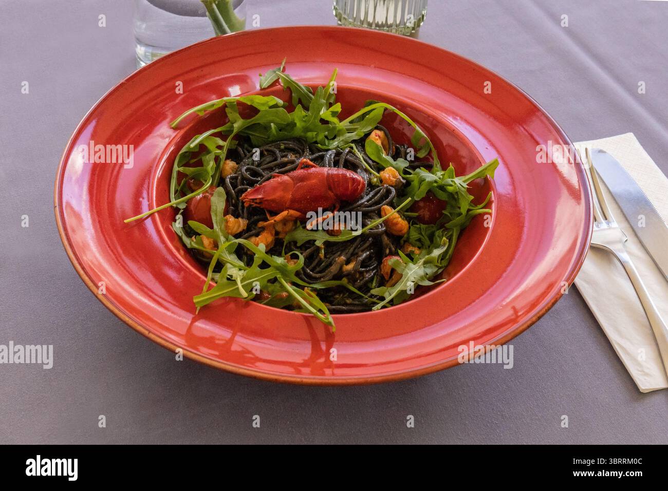 Ein lebendiger Salat mit Meeresfrüchten und saftigen Krustentieren auf frischem Rucola, der kulinarische Handwerkskunst und eine appetitliche Präsentation für Resta hervorhebt Stockfoto