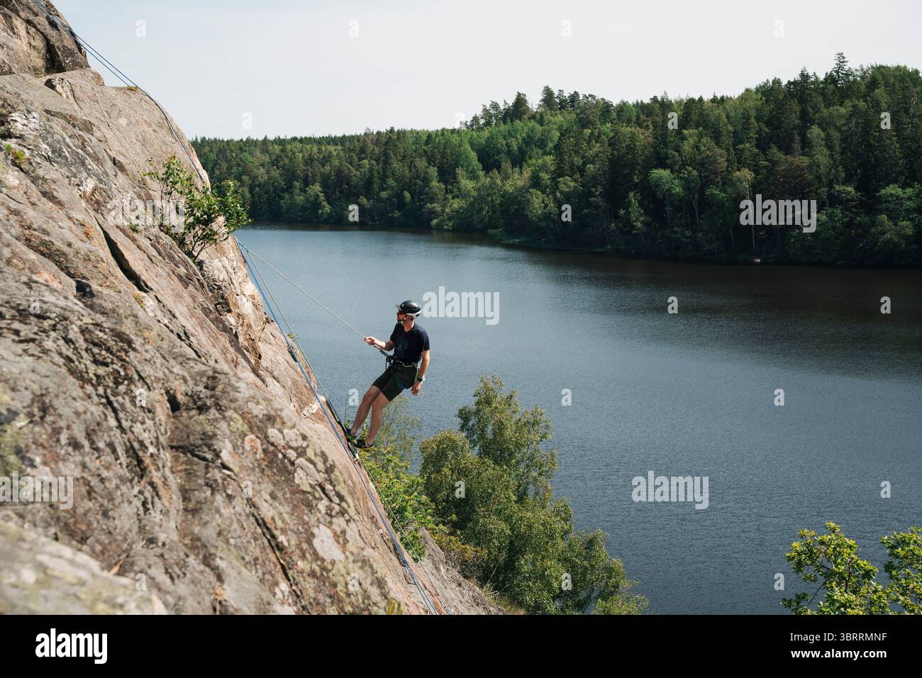 Ein Mann, der einen riesigen Felsen in Stockholm, Schweden, hochklettert Stockfoto