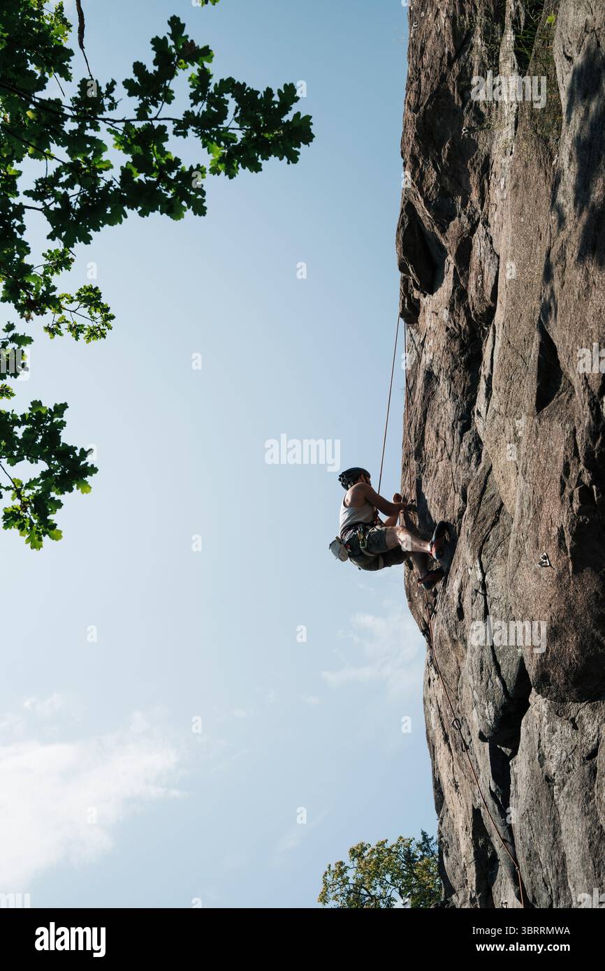 Ein Mann, der in Schweden auf eine Felswände klettert Stockfoto