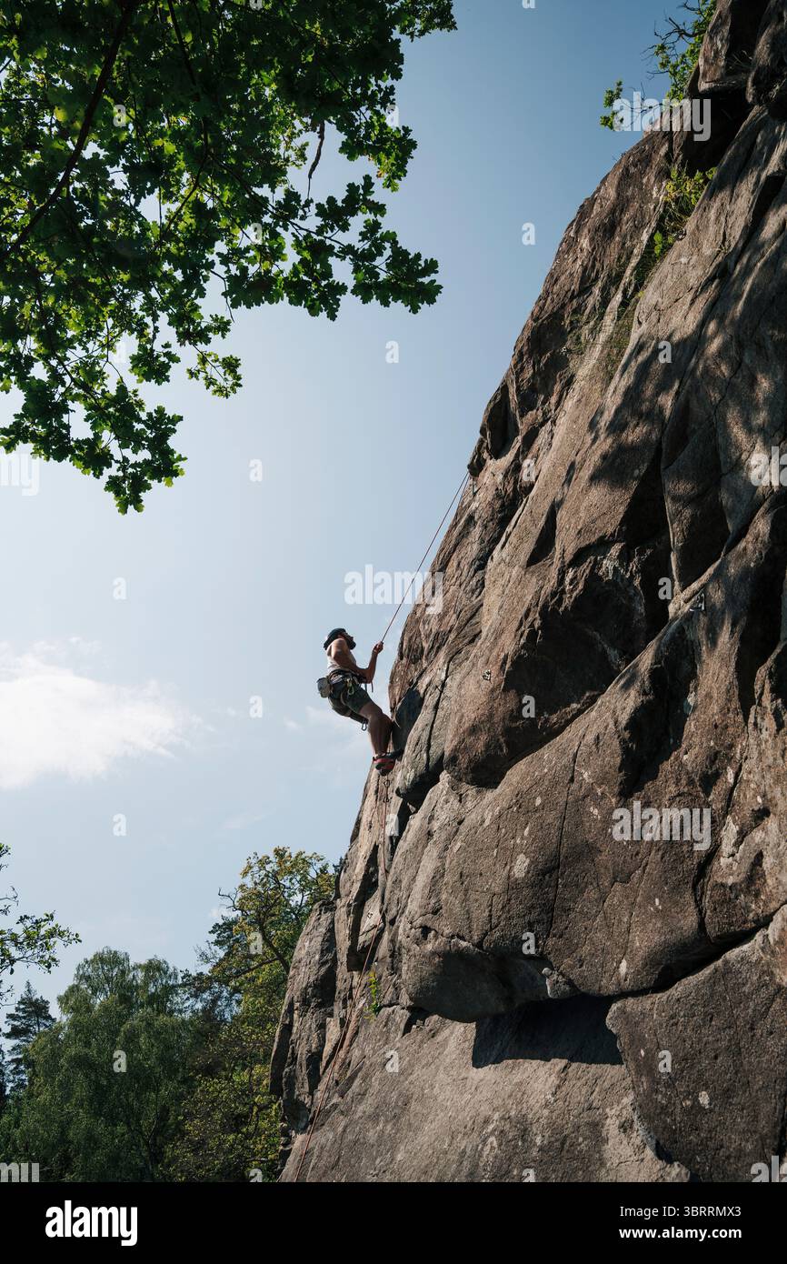Ein Mann, der in Schweden auf einen Felsen klettert Stockfoto