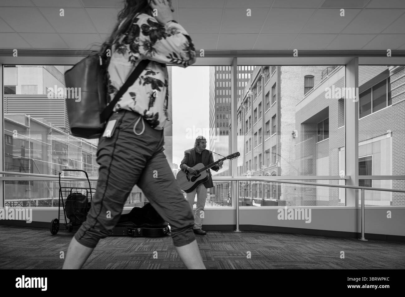 Oktober 2020, des Moines, Iowa, USA: RANDY KONG, ein Busker des Moines tritt in einem leeren Skywalk in der Innenstadt auf. Kong sagte, die Pandemie habe sein Einkommen verwüstet. Es gibt viel weniger Leute, die in der Innenstadt arbeiten, und diejenigen, die es sind, hören nicht auf, ihm zuzuhören oder Geld in seine Gitarrenhülle zu werfen. Die Wirtschaft in der Innenstadt des Moines spürt immer noch die Auswirkungen der im März angeordneten COVID-19-Abschaltung. Sieben Monate nach der Schließung haben Arbeitgeber ihre Arbeitnehmer immer noch von zu Hause aus zu arbeiten. Restaurants, Friseurläden und Einzelhandelsgeschäfte spüren die Auswirkungen. Viele haben Arbeitskräfte und Arbeitsstunden geschlossen oder gekürzt Stockfoto
