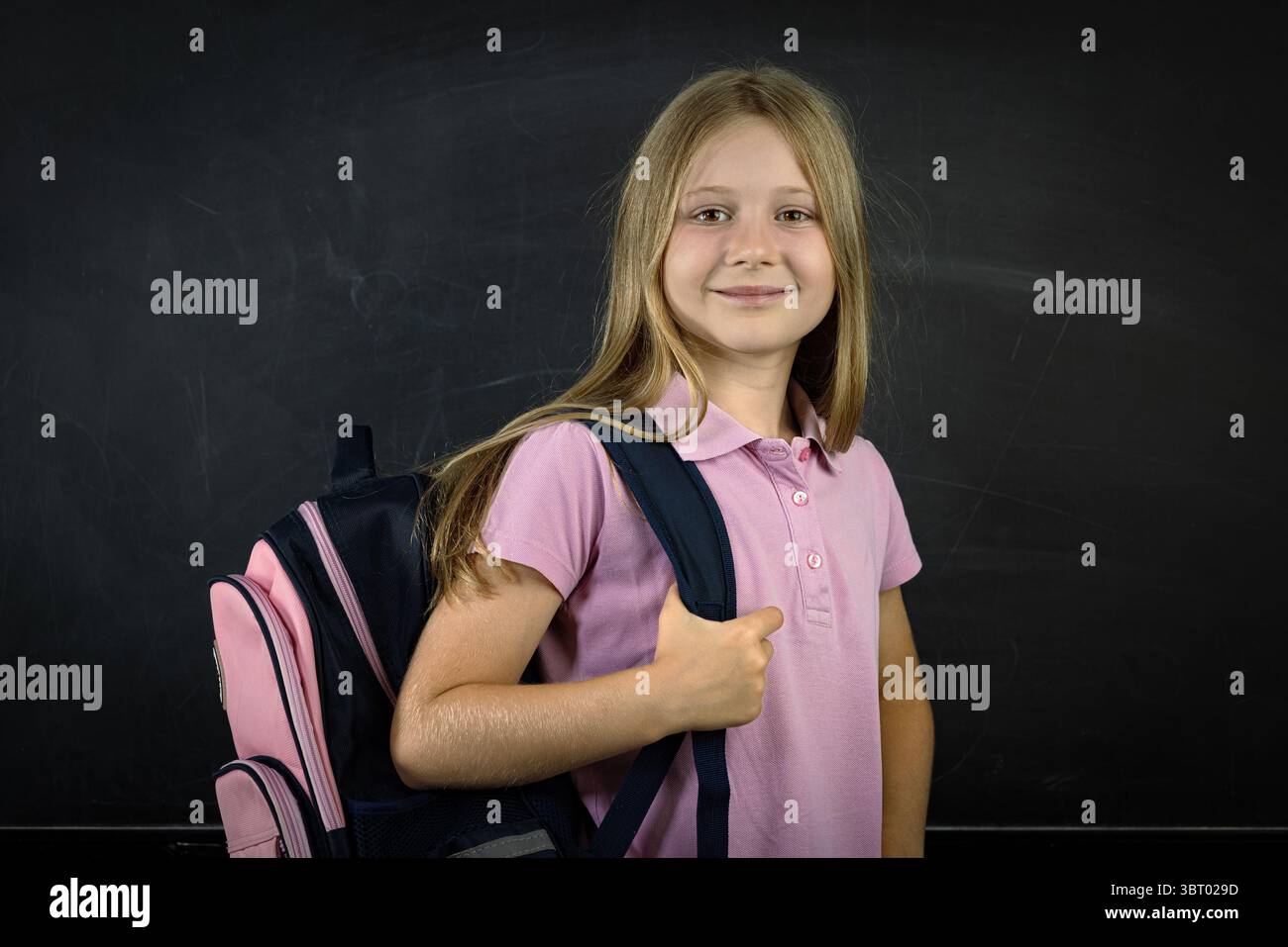 Lächelndes Schulmädchen im Rucksack im Stehen Stockfoto