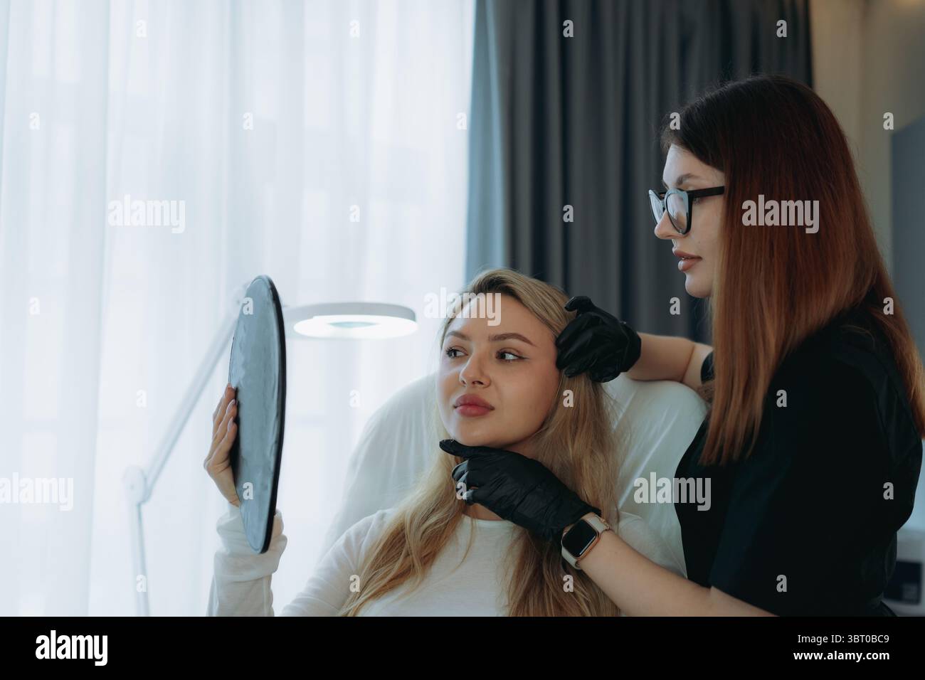 Ästhetische Ärztin bei personalisierter Anti-Aging-Beratung bei einer jungen Kundin. Stockfoto