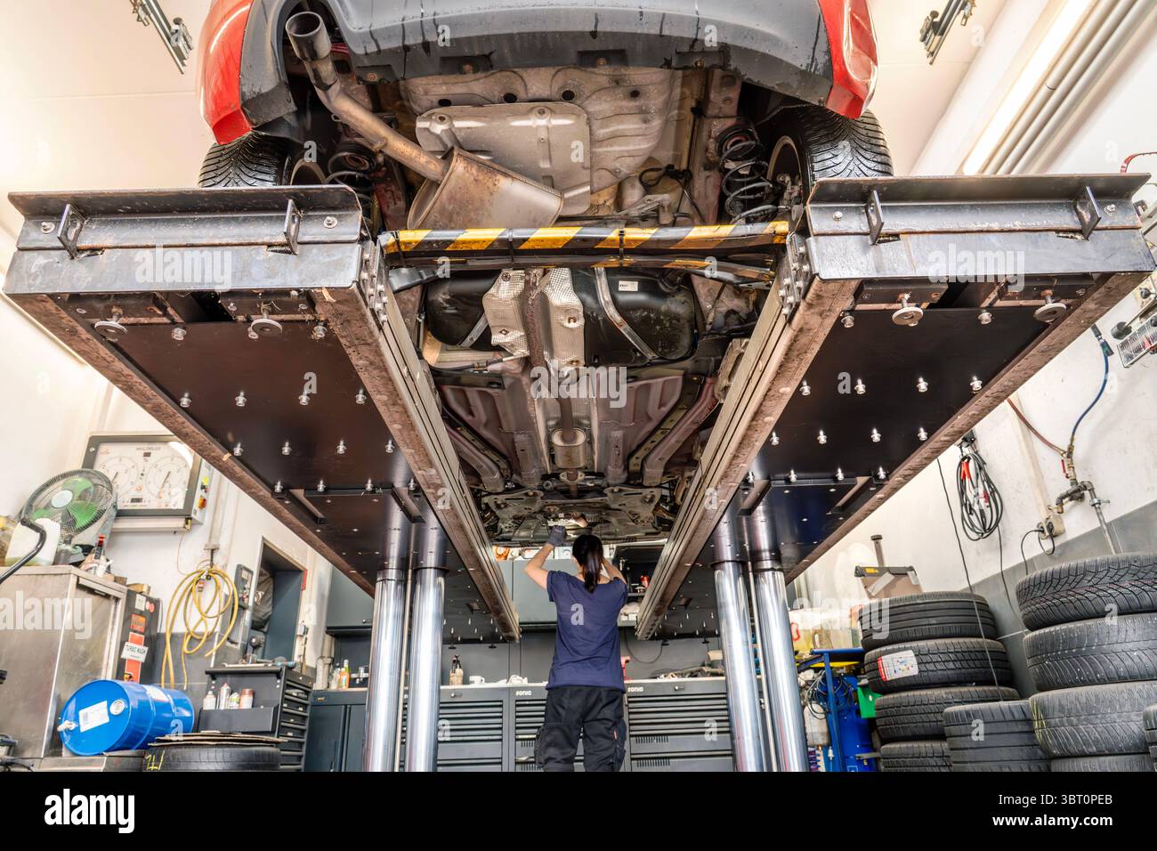 Autowerkstatt, Inspektion eines älteren Alfas auf der Hebebühne, Nähe München, Juli 2025 Deutschland, Nähe München, Juli 2025, Inspektion in der Autowerkstatt, 13 Jahre Alter Alfa Romeo Giulietta auf der Hebebühne, Kfz-Mechanikerin prüft den Unterboden des Fahrzeugs auf Mängel, Bremsen müssen erneuert werden, Arbeitsplatz, Kfz-Werkstatt, Autotechnik, Verkehr, Bayern, *** Autowerkstatt, Inspektion eines älteren Alfa auf der Hebebühne, bei München, Juli 2025 Deutschland, bei München, Juli 2025, Inspektion in der Autowerkstatt, 13-jähriger Alfa Romeo Giulietta auf der Hebebühne, Automechaniker Stockfoto