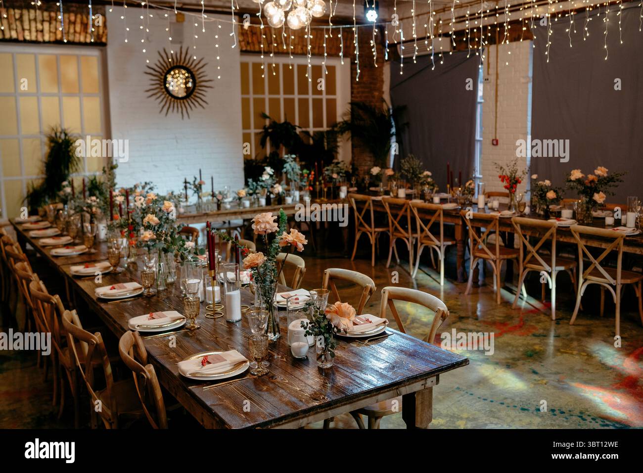 Ein wunderschön dekorierter rustikaler Hochzeitsempfang mit eleganten Blumenarrangements und Ambiente-Beleuchtung sorgt für eine romantische und gemütliche Atmosphäre Stockfoto