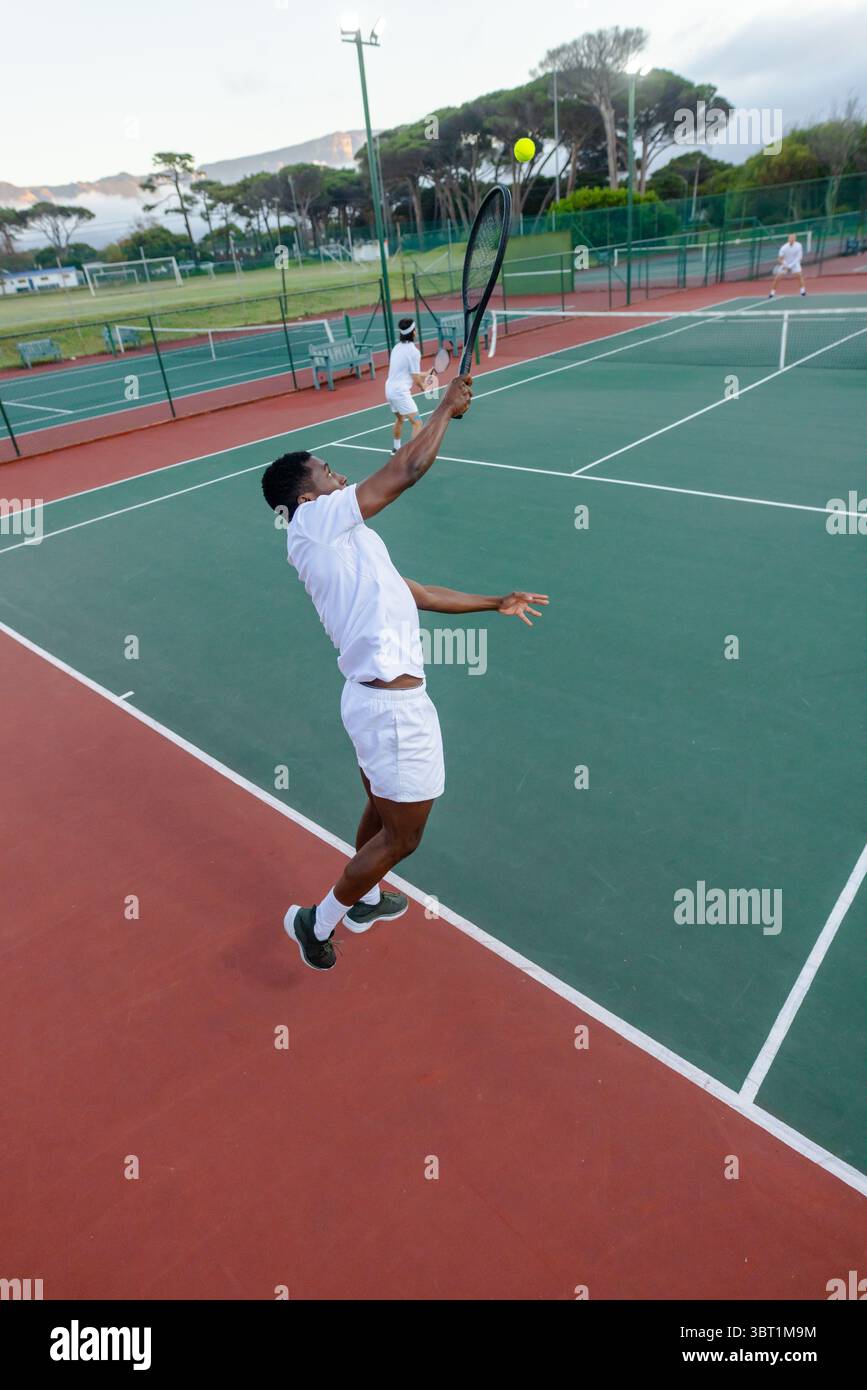 Verschiedene männliche Tennisspieler dienen und spielen auf Hartplatz mit Schlägern und Netz, Kopierraum Stockfoto