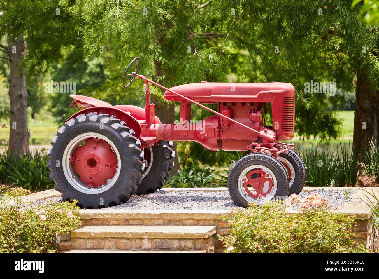 Central Park in der Gemeinde Lakeland, GA USA, mit einer Bogenbrücke über einen Teich, der United States Flag und einem alten internationalen Traktor! Stockfoto