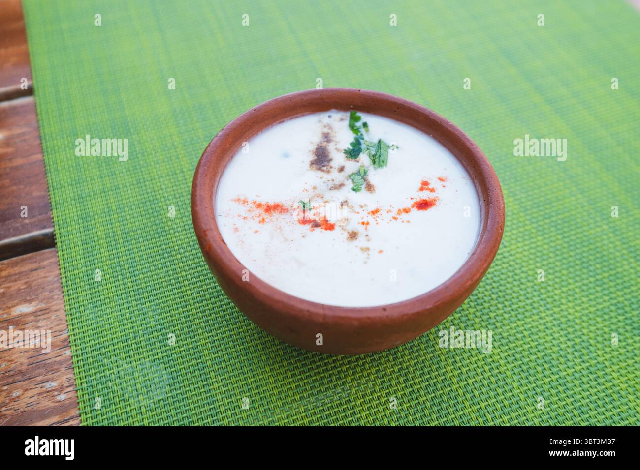 Eine Tasse Joghurt in einer Erdschale auf grüner Tischmatte, Restaurant im Freien Stockfoto