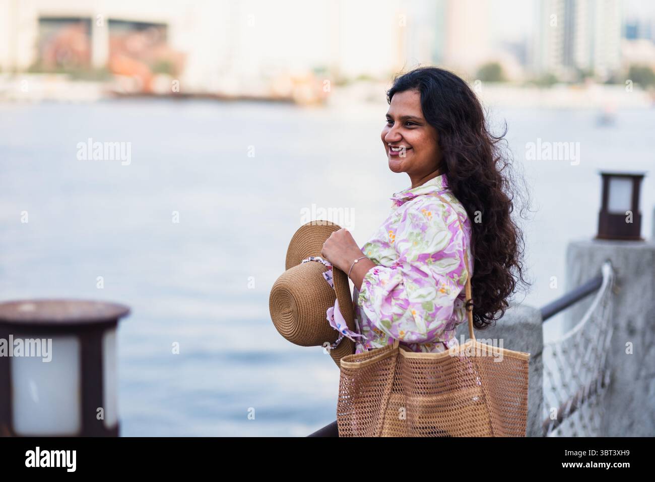 Junge südasiatische Frau in ethnischer Kleidung und Hut erkundet das historische Viertel Al Seef Creek in Dubai, umgeben von traditioneller Emirati Architektur Stockfoto