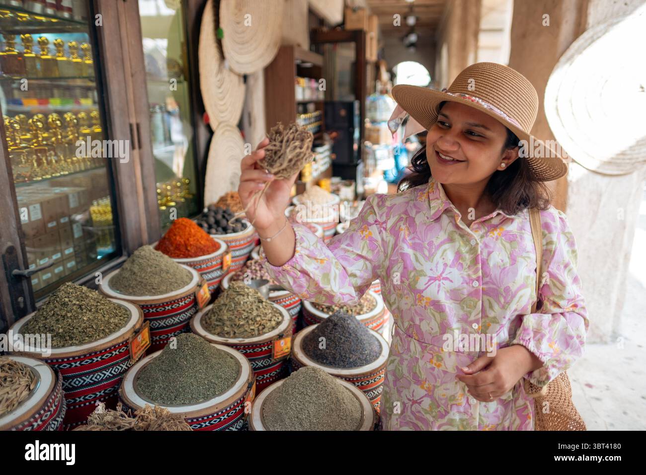 Junge Frau, die lokale Gewürze auf einem lokalen Gewürzmarkt im alten Fahidi Viertel in Dubai kauft Stockfoto