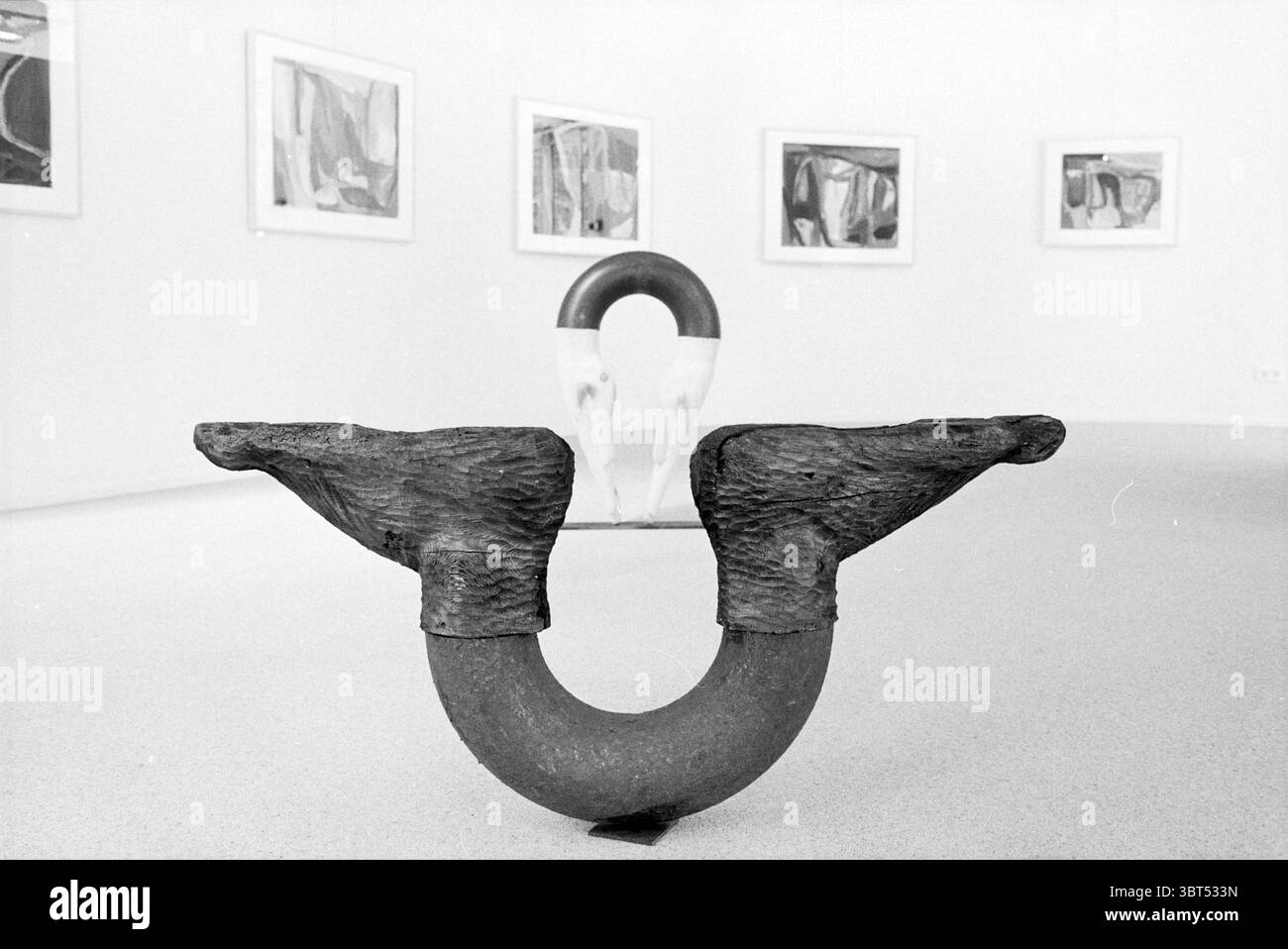Art the Meerse Hoofddorp the Netherlands, Whizgle News, Dutch Desk, Niederlande, 1950 - 2000 am 24-04-1996. Die Abbildung zeigt diese Themen. Die Szene fängt einen durchdachten und minimalistischen Innenraum ein, möglicherweise eine Kunstgalerie oder eine Ausstellungshalle. Im Vordergrund dominiert eine markante künstlerische Skulptur die Komposition. Seine Form ist abstrakt und ähnelt einem ungewöhnlichen, langgestreckten Objekt aus rauem, strukturiertem Material, das möglicherweise Ton oder Stein ähnelt und durch einen dunklen Farbton hervorgehoben wird. Die Enden der Skulptur verwandeln sich in Formen, die auf Flügel oder Ausdrucksformen hinweisen, was zu ihrer Faszination beiträgt Stockfoto