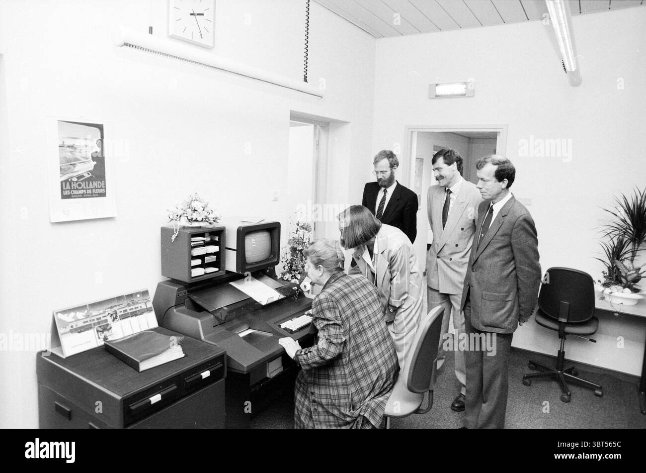 Eröffnung der Station Haarlem Eröffnung der Öffnungen Inbetriebnahme Station Haarlem Niederlande, Whizgle News, Dutch Desk, Niederlande, 1950 - 2000 am 11-05-1989. Die Abbildung zeigt diese Themen. In einem hell beleuchteten, modernen Bürobereich versammelt sich eine Gruppe von fünf Personen um einen Schreibtisch mit einem Vintage-Computer. Die Wände des Raumes sind in einem sauberen weiß gestrichen, was ein Gefühl von Offenheit und Einfachheit vermittelt, verstärkt durch die obenliegende fluoreszierende Beleuchtung, die eine gleichmäßige Helligkeit über die Szene verteilt. In der Mitte konzentriert sich eine Frau am Schreibtisch auf den Computerbildschirm. Sie trägt einen Stockfoto