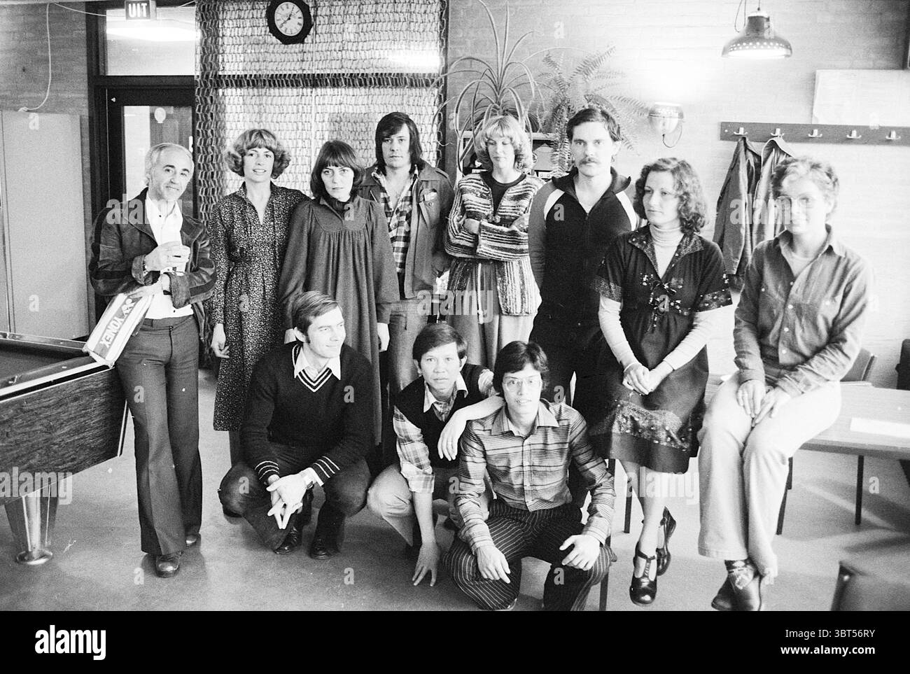 Preisverleihung VNU Badminton-Turnier (Gruppe der Preisträger) Preisverleihung, Whizgle News, Dutch Desk, Niederlande, 1950 - 2000 am 24-04-1978. Diese Themen sind in der Abbildung dargestellt. Die Szene zeigt eine Gruppe von zwölf Individuen, die in zwei Reihen angeordnet sind, um eine ausgewogene Komposition zu schaffen. Die Umgebung scheint ein Innenraum zu sein, wahrscheinlich ein Lounge- oder Tagungsbereich, geprägt von warmen, gedämpften Tönen und einer entspannten Atmosphäre. Im Hintergrund befinden sich Holzelemente und Pflanzen, die der Umwelt einen Hauch von Natur verleihen. Darüber hängt eine Wanduhr, die auf eine ungezwungene Freizeit hinweist Stockfoto