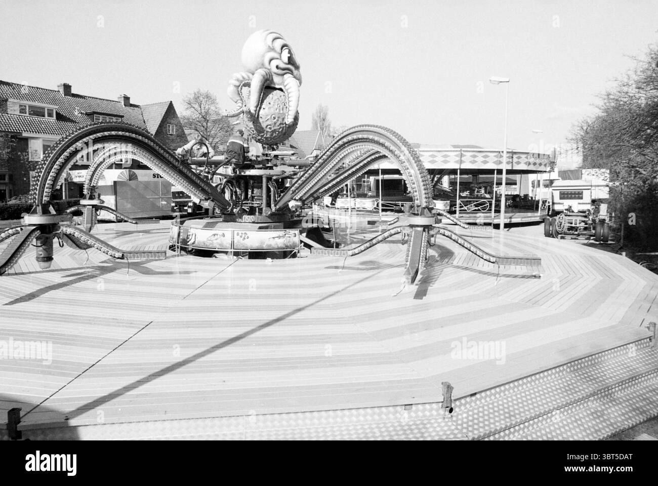 Fair Haarlem Zaanenlaan the Netherlands, Whizgle News, Dutch Desk, Niederlande, 1950 - 2000 am 26-04-1989. Diese Themen werden in der Abbildung angezeigt. Die Szene spielt in einem Vergnügungspark oder einem Messegelände, das durch eine große, kreisförmige Struktur gekennzeichnet ist, die einen Kraken mit langen, wirbelnden Tentakeln in der Mitte zeigt. Die Tentakel drehen sich und Rollen sich nach außen, wodurch eine dynamische und verspielte Form entsteht, die die Aufmerksamkeit auf sich zieht. Der Boden besteht aus Holzpaneelen, die in einem radialen Muster angeordnet sind, mit wechselnden Farben, die einen auffälligen visuellen Effekt erzeugen. Um die zentrale Struktur herum, t Stockfoto