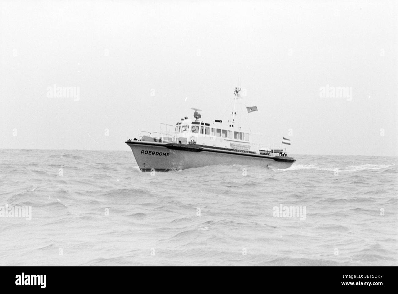 Neues Schiff 'de Roerdomp' Mulder und Rijke Mulder und Rijke Ships, Whizgle News, Dutch Desk, Niederlande, 1950 - 2000 am 04-03-1980. Diese Themen sind in der Abbildung dargestellt. Die Szene zeigt ein Schiff, das durch offene Gewässer navigiert, umgeben von welligen Wellen. Das Boot scheint ein mittelgroßes Schiff zu sein, das sich durch einen schlanken, weißen und schwarzen Rumpf auszeichnet. Sein Name ist an der Seite deutlich sichtbar, im Kontrast zu den dunkleren Farbtönen des Bootes. Über dem Deck flattern verschiedene Fahnen im Wind und verleihen der ansonsten ruhigen Atmosphäre einen Hauch von Bewegung. Das Schiff ist mit mehreren Antennen ausgestattet Stockfoto
