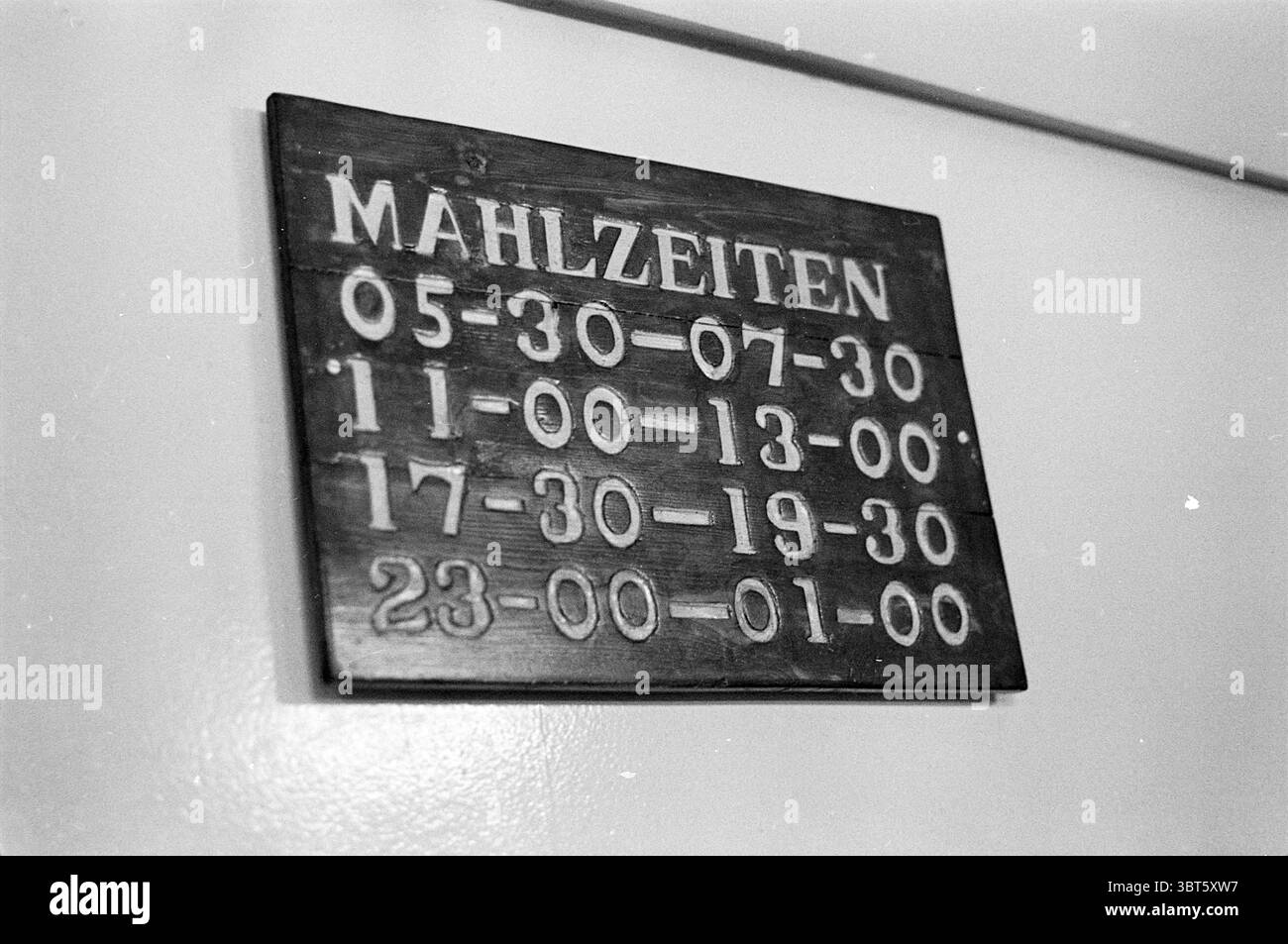 Report Bohren Rig Trans Ocean 1 Report, Whizgle News, Dutch Desk, Niederlande, 1950 - 2000 am 25-11-1975. Dies sind die Themen im Bild. Die Szene zeigt ein Holzbrett, das gut sichtbar an einer Wand angebracht ist. Das Brett ist dunkel, wahrscheinlich fleckig, um sein rustikales Aussehen zu verstärken. Die Handwerkskunst des Holzes ist offensichtlich, mit sichtbaren Körnungen und Texturen, die ihm ein stabiles und traditionelles Gefühl verleihen. Auf dem Brett gibt es eine Reihe von Zahlen, die gut organisiert angeordnet sind, jede in unterschiedlichen Zeitfenstern. Die Zahlen sind geschnitzt, wodurch eine haptische Qualität entsteht, die näher hereinzukommen einlädt Stockfoto