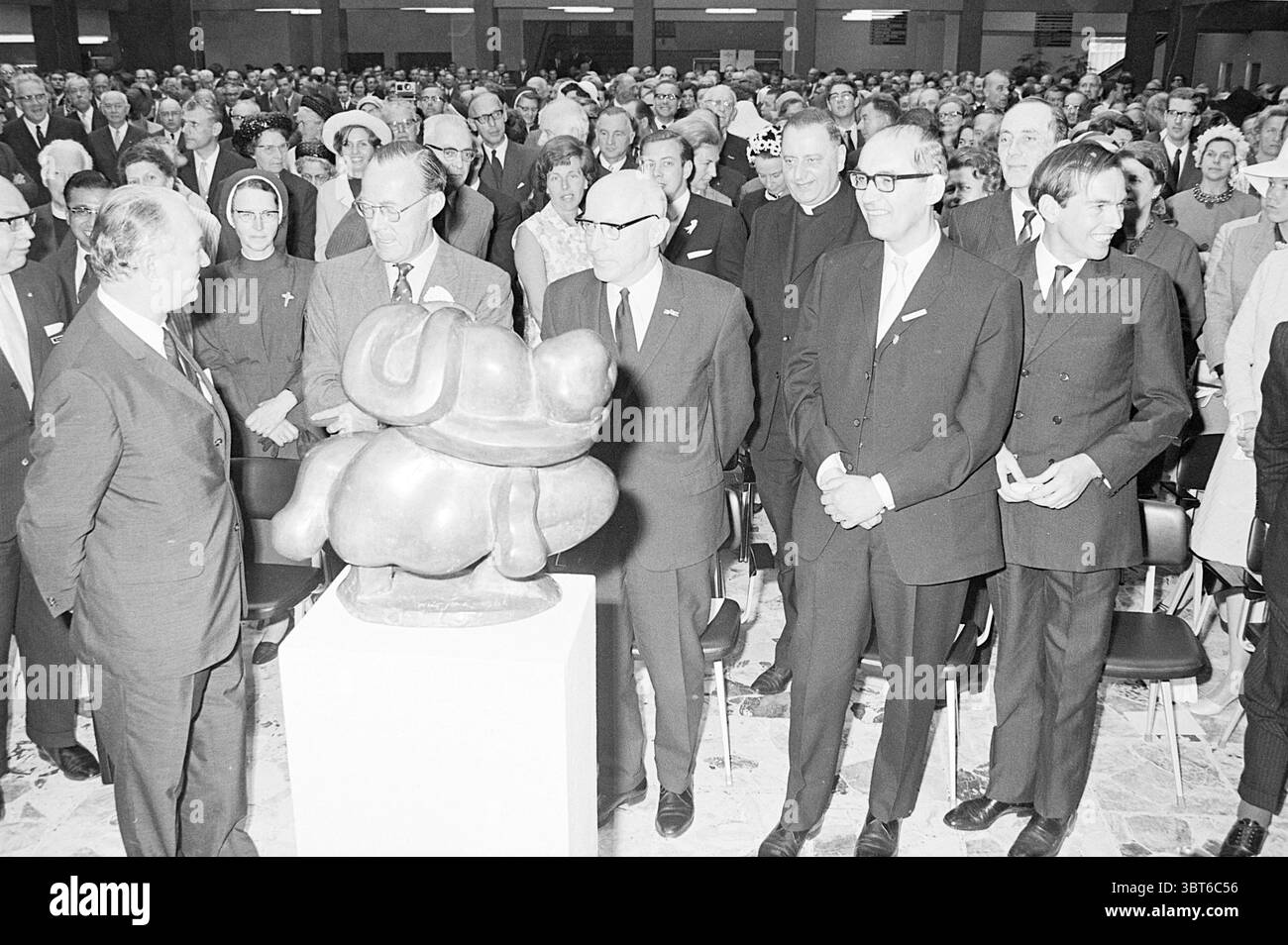 Eröffnung des St. Lucas Krankenhauses durch Prinz Bernhard Eröffnung der Öffnungen Eröffnung, Whizgle News, Dutch Desk, Niederlande, 1950 - 2000 am 08-06-1968. Die Abbildung zeigt diese Themen. Die Szene ist voll von einer großen Menschenmenge, die sich in einem Innenraum versammelt, wahrscheinlich zu einer Veranstaltung oder Feier. Im Vordergrund steht eine Gruppe von Männern in unmittelbarer Nähe zu einer markanten Skulptur, die wie ein stilisierter Hund geformt ist. Die Skulptur ist auf einem Sockel ausgestellt und lenkt die Aufmerksamkeit der Menschen in der Nähe. Die Leute tragen formelle Kleidung, einschließlich dunkler Anzüge und Krawatten, und einige tragen eine Brille Stockfoto