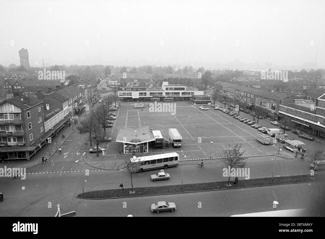 Market Square IJmuiden aus dem Bunker IJmuiden Velsen IJmuiden Marktplein The Netherlands, Whizgle News, Dutch Desk, Niederlande, 1950 - 2000 am 01-11-1978. Dies sind die Themen im Bild. Die Szene ist ein weitläufiger Blick auf einen Stadtplatz, der eine etwas öde urbane Landschaft unter einem vorherrschenden grauen Himmel zeigt, was auf bewölktes Wetter hindeutet. Der Platz ist von mehreren Gebäuden umgeben, überwiegend flachen Gebäuden, die eine Mischung aus Wohn- und Geschäftsarchitektur zeigen, die durch einen unverwechselbaren Stil der Mitte des Jahrhunderts gekennzeichnet ist. Im Vordergrund ist das Quadrat selbst weitgehend unbewohnt, außer Stockfoto