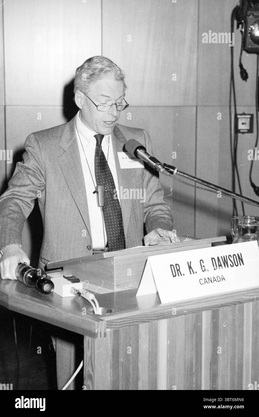 MSD-Symposium im RAI Amsterdam Niederlande, Whizgle News, Dutch Desk, Niederlande, 1950 - 2000 am 16-03-1984. Diese Themen sind in der Abbildung dargestellt. In einer formellen Umgebung steht ein Mann auf einem Podium, das sich vor dem Raum konzentrieren lässt. Er trägt einen maßgeschneiderten Anzug, ein helles Hemd und eine gemusterte Krawatte, die ein Gefühl von Professionalität ausstrahlt. Der Mann mit silbernen Haaren und Brille scheint ein Publikum zu sprechen, mit leicht nach unten gerichtetem Blick, wahrscheinlich auf Noten oder eine Rede vor ihm. Das Podium selbst besticht durch ein klares und minimalistisches Design mit einem horizontalen p Stockfoto