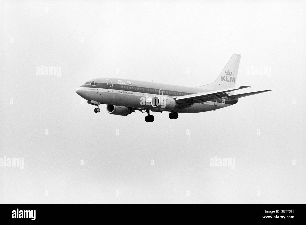 Mehrere Landungsflugzeuge, Whizgle News, Dutch Desk, Niederlande, 1950 - 2000 am 01-04-1993. Diese Themen sind in der Abbildung dargestellt. In dieser Szene wird ein kommerzielles Flugzeug während des Fluges gefangen genommen, das vor dem Hintergrund des bewölkten Himmels absteigt. Das Flugzeug mit seinem klaren Design zeigt ein hellgraues Äußere mit auffälligen blauen Markierungen, darunter das Logo der Fluggesellschaft. Das Flugzeug hat einen kurzen, robusten Rumpf und markante Flügelformen, die auf sein Modell hinweisen. Die Wolken sind ein weiches, einheitliches Grau, was zu einer etwas bewölkten Stimmung beiträgt. Die Beleuchtung wird gestreut, was der Szene eine sanfte, gleichmäßige Atmosphäre verleiht Stockfoto