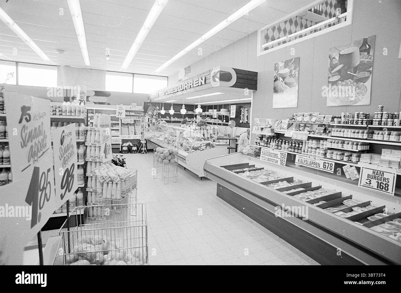 Intr. Beentjes -HeemskerkZuidervaart-Heemskerk Spar Super-Uitgeest. Innenausstattung, Whizgle News, Dutch Desk, Niederlande, 1950 - 2000 am 01-05-1974. Diese Themen werden in der Abbildung angezeigt. Die Szene zeigt das Innere eines Lebensmittelgeschäfts, das durch klare Linien und ein gut organisiertes Layout gekennzeichnet ist. Der Raum ist geräumig, mit einer hellen Deckenbeleuchtung, die die verschiedenen Bereiche des Stores beleuchtet. Auf der einen Seite sind die Regale mit einer Reihe von Konserven, Gewürzen und verpackten Artikeln ausgestattet, die eine warme Farbpalette – Rot, Grün und Gelb – präsentieren, die sich von den neutralen Farben der Wände und des Bodens abhebt Stockfoto