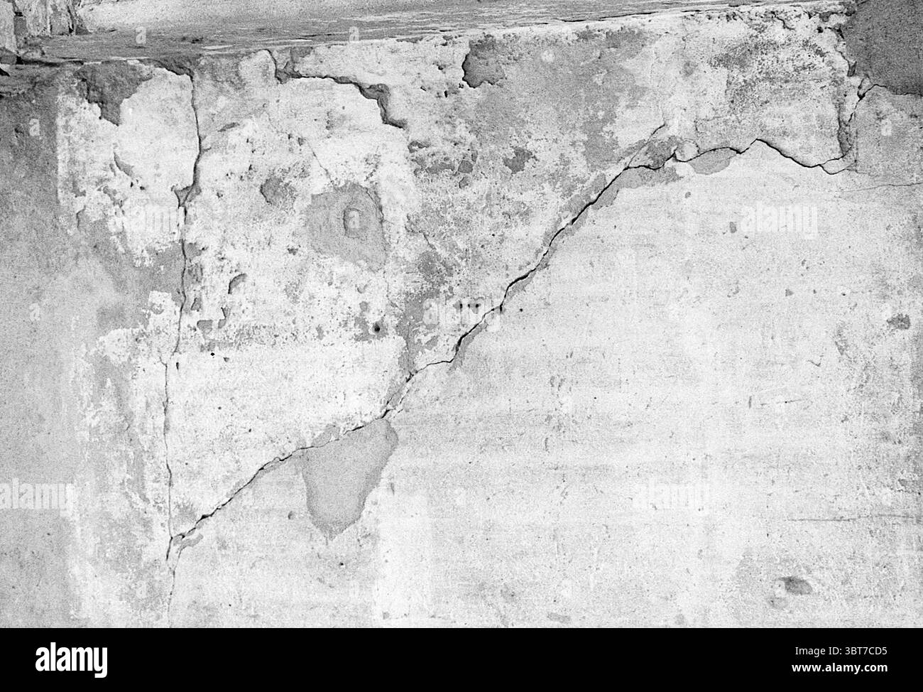 Gebäude mit Rissen. Buildings, Whizgle News, Dutch Desk, Niederlande, 1950 - 2000 am 28-03-1974. Das Bild enthält diese Themen. Die Szene zeigt eine strukturierte Wand mit Anzeichen von Alter und Verschleiß. Die Oberfläche ist in erster Linie ein gedämpftes Grau mit Farbvariationen, die auf Tiefe und Charakter hinweisen. Risse in der Spinne an der Wand, die deutlich die Brüche zeigt, die die ansonsten flache Ausdehnung stören. Einige Bereiche sind mit helleren Grau oder weichem Beige gefärbt, was auf Feuchtigkeit oder eventuell frühere Reparaturen hinweist. Die Zusammensetzung ist stark, wobei die Risse dynamische Linien erzeugen, die den führen Stockfoto