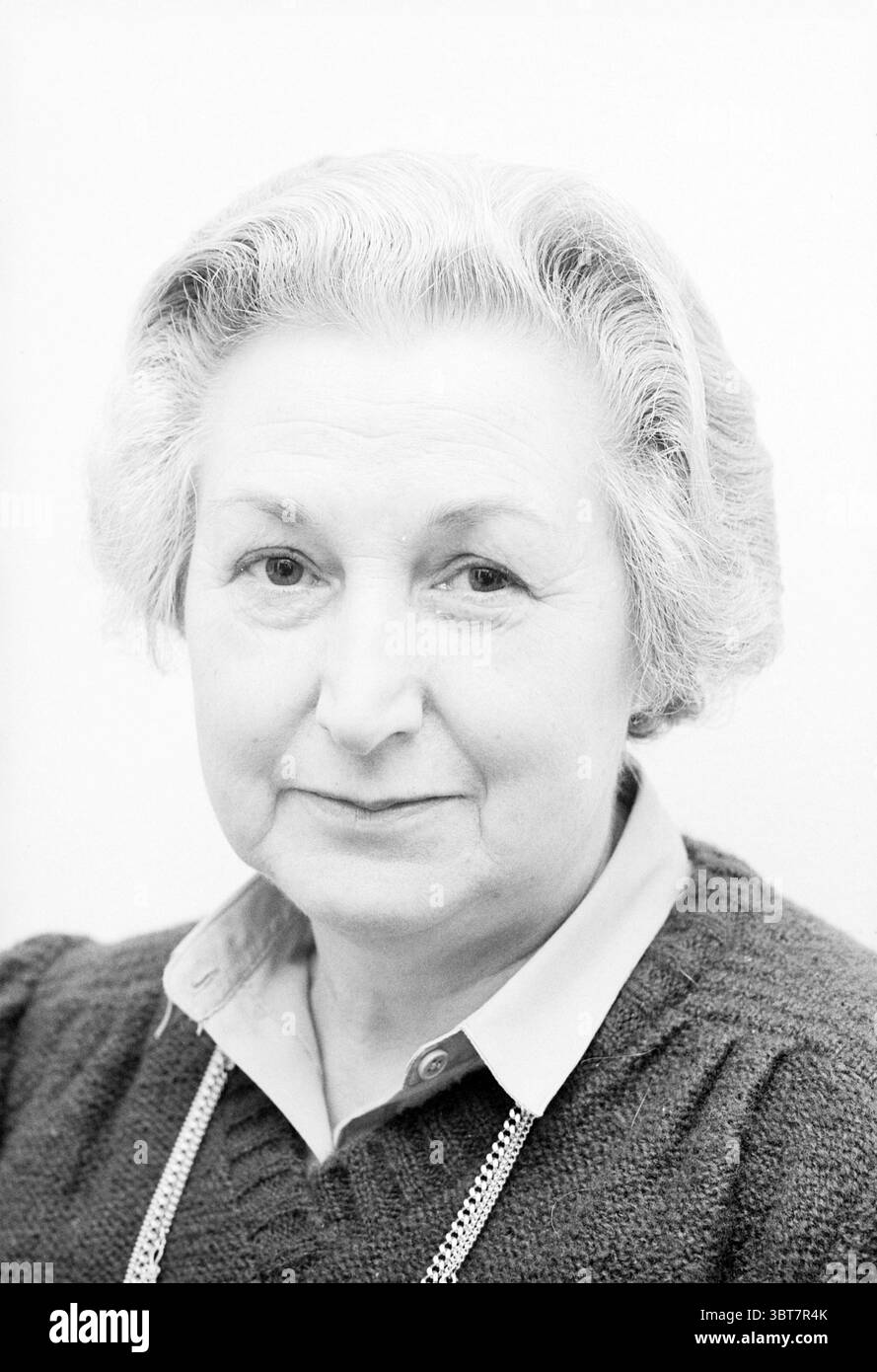 Porträt Frau Bronsveld + Robert Schoondergang council Members IJmuiden Municipal Council, Whizgle News, Dutch Desk, Niederlande, 1950 - 2000 am 27-03-1980. Diese Themen werden in der Abbildung angezeigt. Die Szene zeigt eine ältere Frau mit einem komponierten Ausdruck. Sie hat weiches, welliges Haar, das überwiegend grau ist und ordentlich gestylt ist, um ihr Gesicht einzurahmen. Ihr Teint wirkt fair, mit subtilen Alterserscheinungen, die auf Weisheit und Erfahrung hindeuten. Die Einrichtung ist minimalistisch, mit einem hellen, neutralen Hintergrund, der ihre Eigenschaften ohne Ablenkung betont. Sie trägt einen dunklen, gestrickten Pullover, was im Gegensatz dazu steht Stockfoto