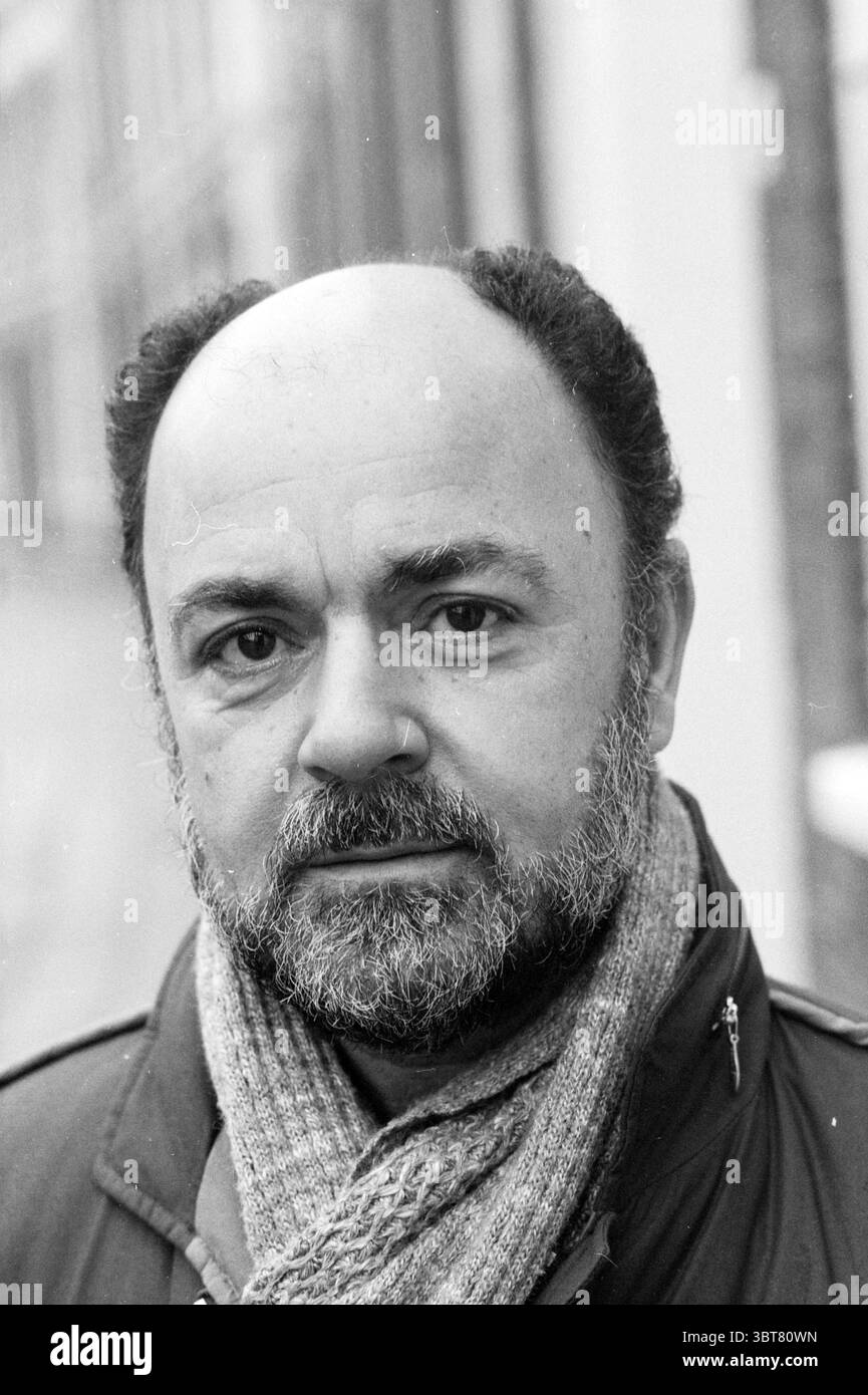 Herr Sevil Gemeindeentwickler Frans Halsbuurt Ausländer Nachbarschaften Gemeindezentren örtliche Geschäfte Trainingszentren, Whizgle News, Dutch Desk, Niederlande, 1950 - 2000 am 24-11-1983. Die Abbildung zeigt diese Themen. In der Szene steht ein Mann mittleren Alters in einer leichten Nahaufnahme und strahlt eine nachdenkliche, aber dennoch zugängliche Präsenz aus. Sein Haar ist hauptsächlich Salz-und-Pfeffer, mit einer auffälligen Glatze oben. Ein gepflegter Bart umrahmt sein Gesicht, verleiht seinem Ausdruck Tiefe und betont seine Gesichtszüge. Er trägt einen dunklen Mantel, der warm und funktional wirkt. Umwickelt um seinen nec Stockfoto