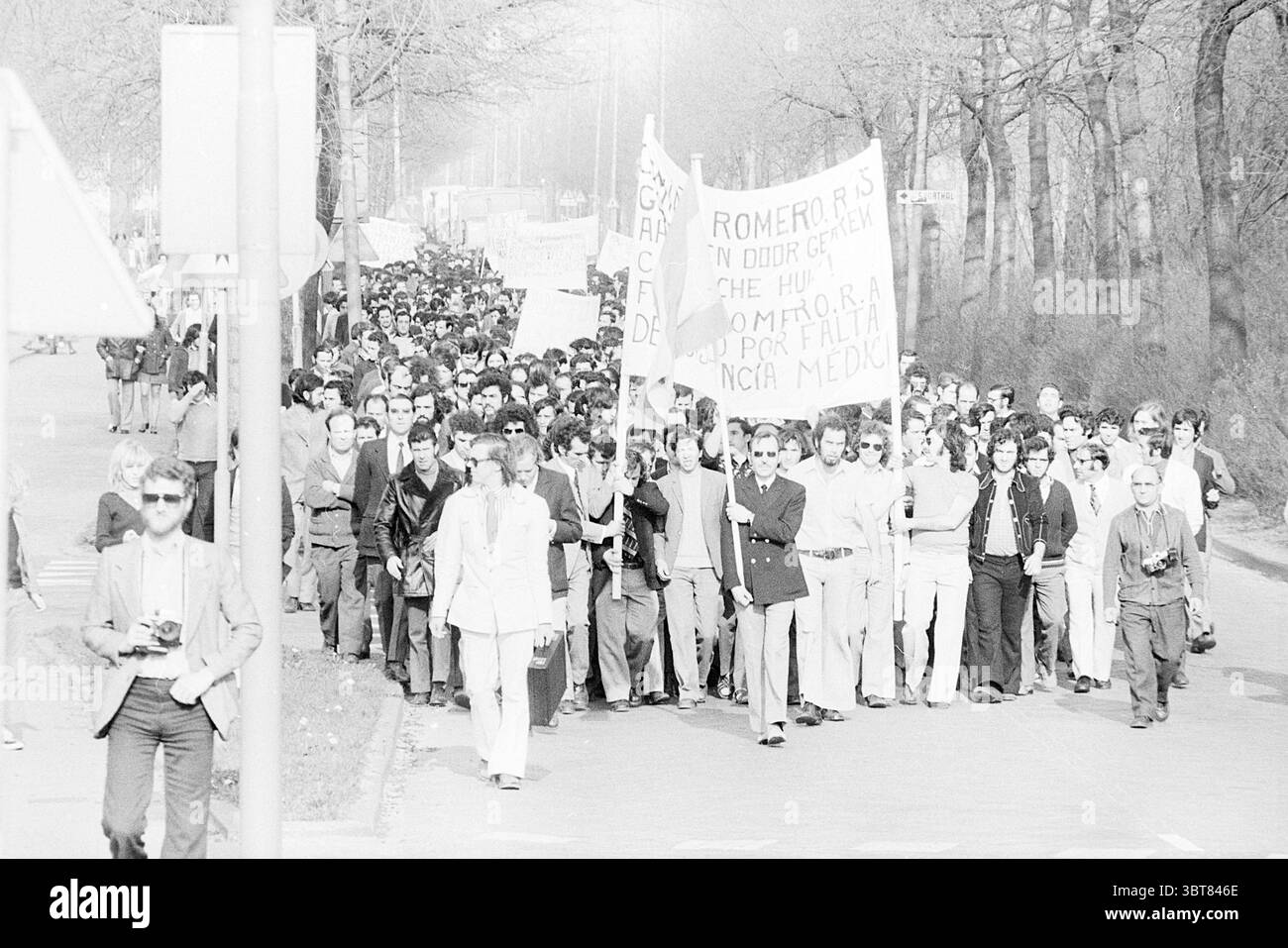 Demonstration spanischer Gastarbeiter in Beverwijk Demonstration, Whizgle News, Dutch Desk, Niederlande, 1950 - 2000 am 04-04-1974. Die Abbildung zeigt diese Themen. Eine große Menschenmenge versammelt sich auf einer breiten Straße, die ein starkes Gefühl von Einheit und Zweck schafft. Die Menschen tragen verschiedene Kleidungsstücke, was auf eine Mischung aus legeren und formelleren Kleidungsstilen der damaligen Zeit hindeutet. Viele Personen tragen Fahnen und Banner; die Schilder sind auffällig und zeigen Slogans, die den Grund widerspiegeln, für den die Gruppe zusammengekommen ist, obwohl spezifische Botschaften nicht erkennbar sind. Die Menge Stockfoto
