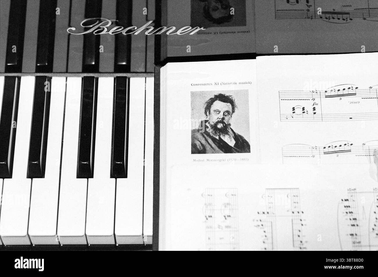 Ed de Rijk Bewunderung, Whizgle News, Dutch Desk, Niederlande, 1950 - 2000 am 12-03-1995. Das Bild enthält diese Themen. Eine Hochglanz-Schwarz-weiß-Szene präsentiert ein reiches Zusammenspiel von Texturen und Details. Im Mittelpunkt steht ein Klavier mit schlanken, polierten Tasten, die einen sanften Lichtschimmer reflektieren und in symmetrischen Schwarzweißmustern angeordnet sind. Um die Tasten herum befinden sich teilweise sichtbare Notenblätter – eine komplexe Anordnung von Noten und Notenblättern, die mit Noten durchsetzt sind, was auf ein lebhaftes Musikstück im Gange ist. Unter den Blättern befindet sich ein Porträt einer klassischen Komposition Stockfoto